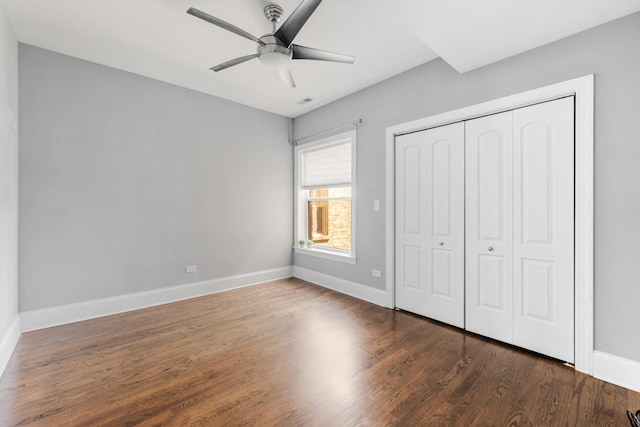 unfurnished bedroom featuring baseboards, wood finished floors, a closet, and ceiling fan