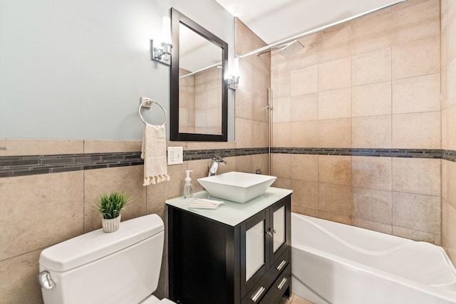 bathroom featuring tile walls, toilet, vanity, and tub / shower combination