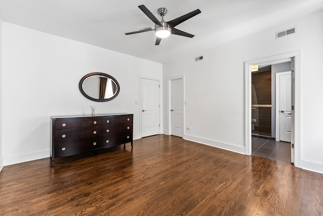 unfurnished bedroom with baseboards, wood finished floors, ceiling fan, and ensuite bathroom