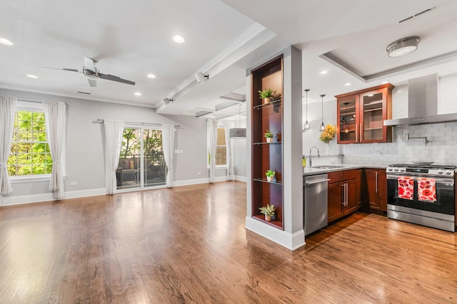 kitchen with stainless steel appliances, wall chimney range hood, open floor plan, ceiling fan, and backsplash