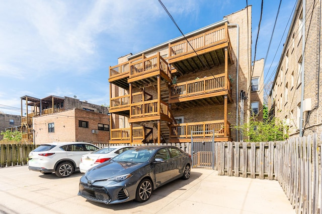 view of building exterior with fence and uncovered parking