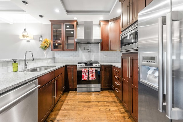 kitchen with appliances with stainless steel finishes, a sink, wall chimney range hood, decorative backsplash, and recessed lighting