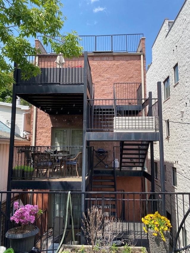 back of property with a balcony and stairway
