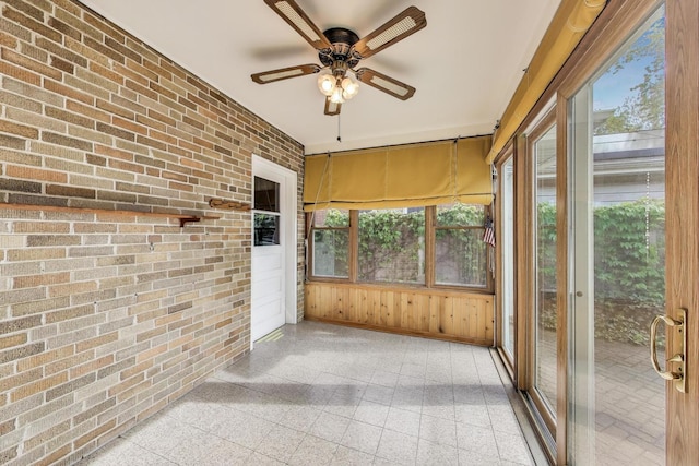 unfurnished sunroom featuring a ceiling fan and plenty of natural light