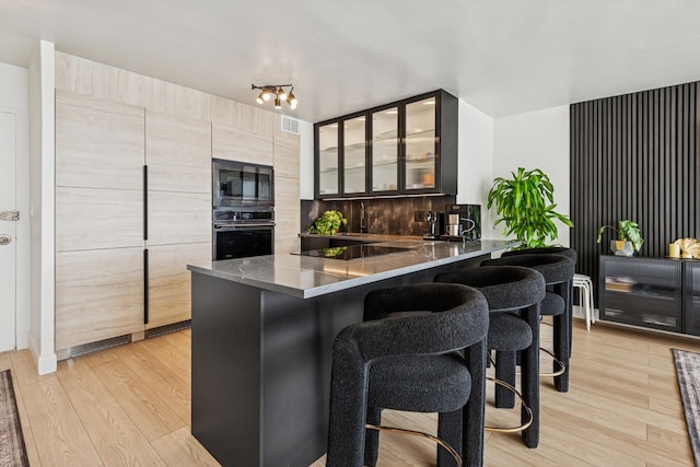 6301 N Sheridan Rd Unit 17J, Chicago, IL 60660 - kitchen featuring wall oven, built in microwave, a kitchen breakfast bar, black electric cooktop, and glass insert cabinets