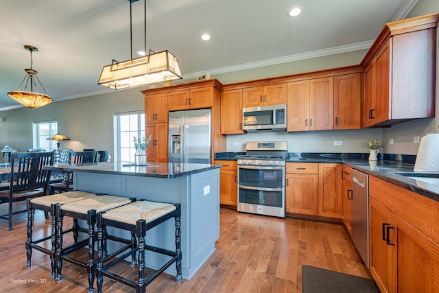 25549 Sara Ct, Channahon, IL 60410 - kitchen with appliances with stainless steel finishes, ornamental molding, brown cabinetry, light wood-type flooring, and a kitchen breakfast bar