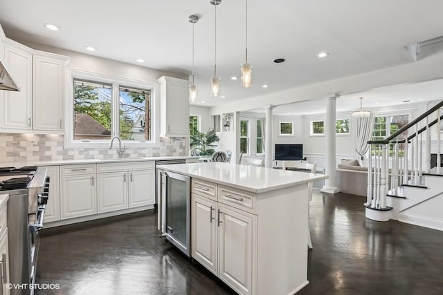 kitchen with high end stainless steel range oven, wine cooler, a sink, dark wood-style floors, and ornate columns