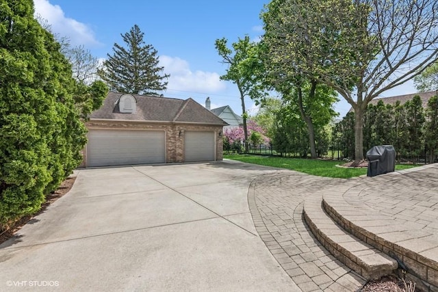 view of side of property featuring brick siding, concrete driveway, a garage, and an outdoor structure
