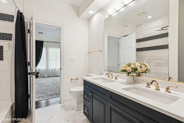 bathroom featuring toilet, double vanity, recessed lighting, a shower, and baseboards