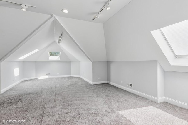additional living space featuring a skylight, vaulted ceiling, carpet, and baseboards