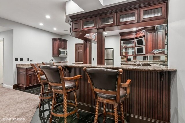 indoor wet bar with appliances with stainless steel finishes, recessed lighting, dark tile patterned flooring, and baseboards