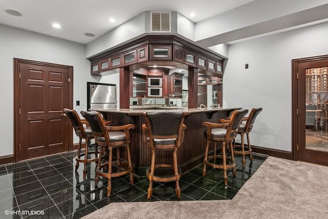 indoor wet bar featuring freestanding refrigerator, dark tile patterned floors, baseboards, and recessed lighting