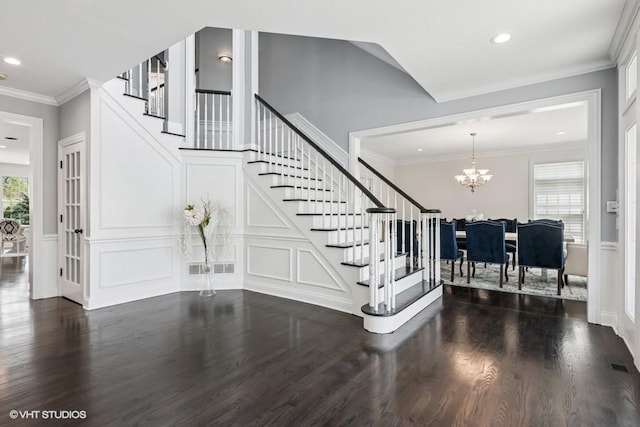 stairs featuring a chandelier, wood finished floors, a decorative wall, recessed lighting, and wainscoting