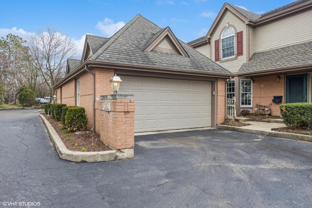view of front facade featuring brick siding, driveway, a garage, and a shingled roof