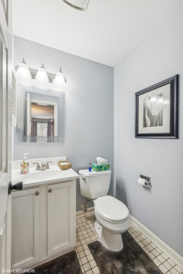 bathroom featuring toilet, baseboards, and vanity
