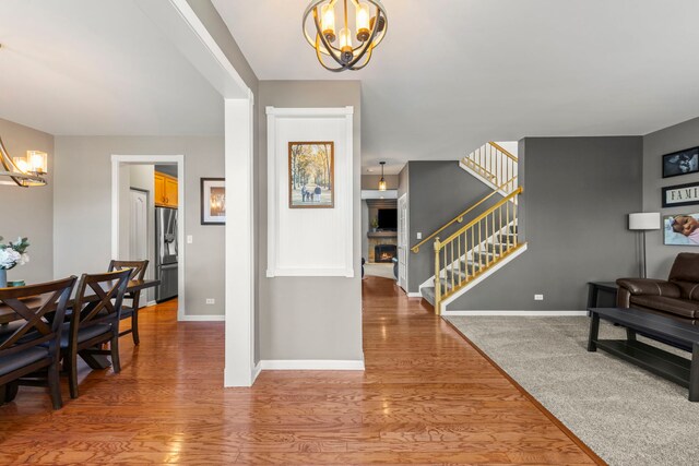 401 Manchester Rd, Oswego, IL 60543 - foyer entrance featuring a chandelier, stairs, a warm lit fireplace, and baseboards