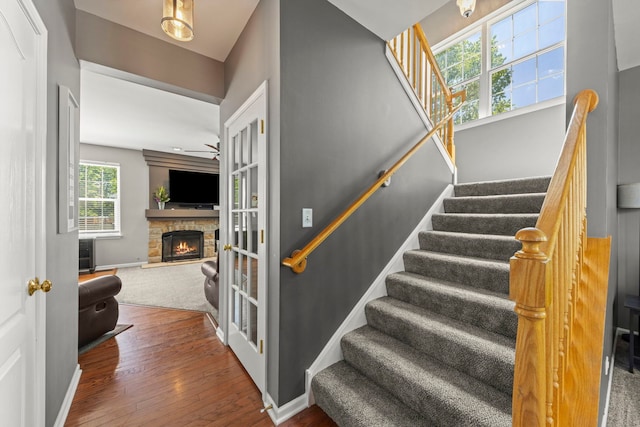 401 Manchester Rd, Oswego, IL 60543 - stairway featuring a stone fireplace, wood-type flooring, baseboards, and ceiling fan
