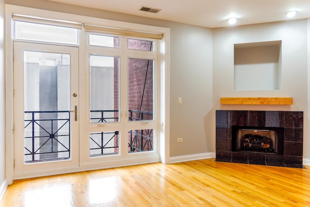 doorway with wood finished floors, a fireplace, and baseboards