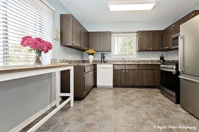 716 Lagoon Ter, Round Lake Beach, IL 60073 - kitchen with appliances with stainless steel finishes, stone finish floors, dark brown cabinetry, and a sink
