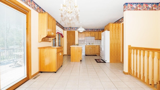 kitchen with freestanding refrigerator, a chandelier, a sink, light tile patterned floors, and light countertops