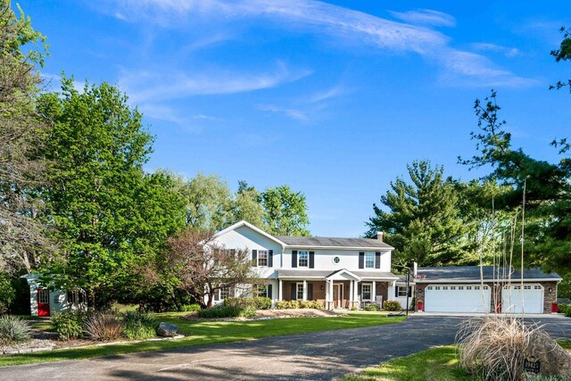 19423 Lakeside Ln, Bloomington, IL 61705 - traditional home featuring asphalt driveway, an attached garage, a front lawn, and a chimney