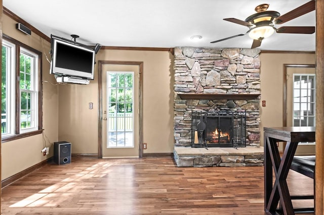 19423 Lakeside Ln, Bloomington, IL 61705 - unfurnished living room with ceiling fan, crown molding, wood finished floors, baseboards, and a stone fireplace