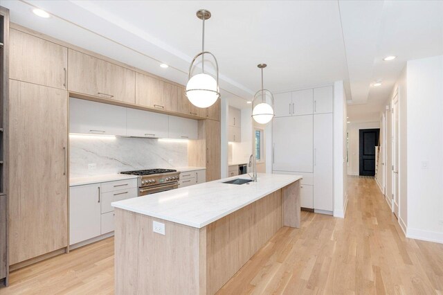 1542 W Highland Ave, Chicago, IL 60660 - kitchen with a sink, light brown cabinets, stainless steel stove, light wood-style floors, and decorative backsplash