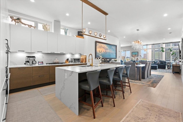 2773 N Hampden Ct Unit Ph03, Chicago, IL 60614 - kitchen featuring modern cabinets, stainless steel gas cooktop, open floor plan, a center island with sink, and healthy amount of natural light