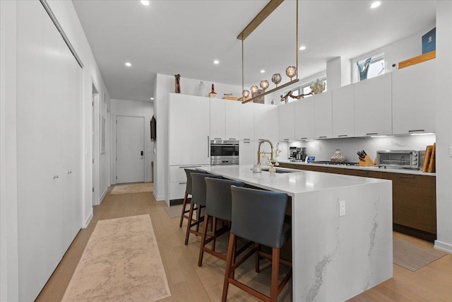 2773 N Hampden Ct Unit Ph03, Chicago, IL 60614 - kitchen featuring a kitchen breakfast bar, a kitchen island with sink, light countertops, white cabinets, and stainless steel gas stovetop