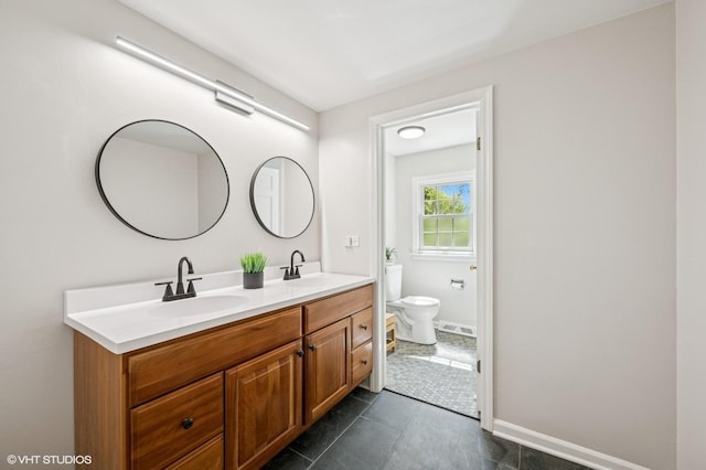 bathroom with toilet, double vanity, baseboards, and tile patterned floors