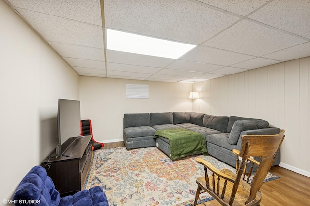 living room featuring a drop ceiling, wood finished floors, and baseboards