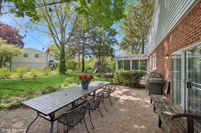 view of patio / terrace featuring outdoor dining area, a grill, a playground, and a sunroom