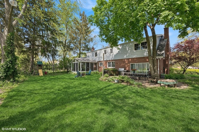 view of grassy yard featuring a sunroom and a patio area