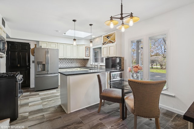 3300 Overland Pass, Northbrook, IL 60062 - kitchen featuring appliances with stainless steel finishes, a peninsula, dark countertops, backsplash, and decorative light fixtures