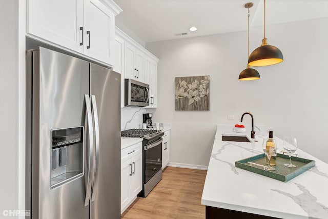 5201 S Wabash Ave, Chicago, IL 60615 - kitchen featuring appliances with stainless steel finishes, a sink, white cabinets, light wood finished floors, and light stone counters