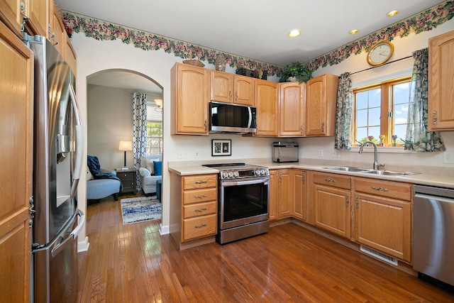 689 Revere St, Bourbonnais, IL 60914 - kitchen featuring stainless steel appliances, a sink, dark wood-style flooring, arched walkways, and light countertops