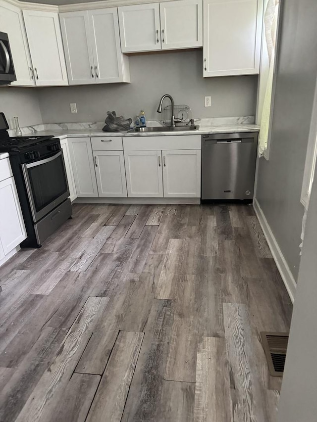 701 E 89th Pl, Chicago, IL 60619 - kitchen with appliances with stainless steel finishes, a sink, dark wood-type flooring, white cabinetry, and light countertops