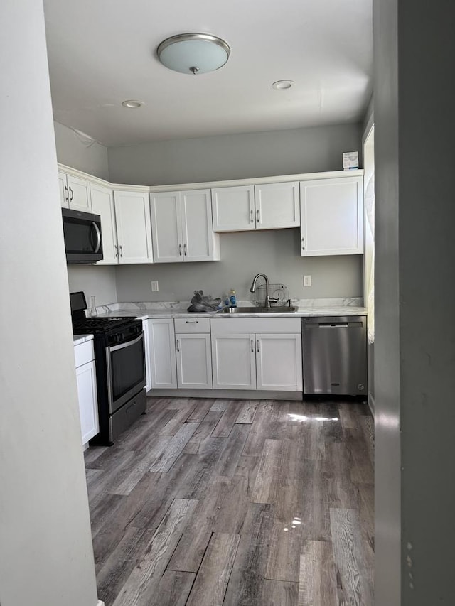 701 E 89th Pl, Chicago, IL 60619 - kitchen featuring stainless steel appliances, a sink, white cabinets, dark wood finished floors, and light countertops