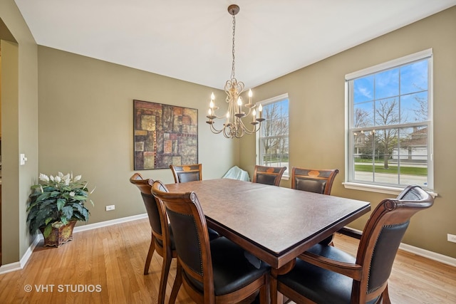 dining area with a chandelier, light wood-style flooring, and baseboards