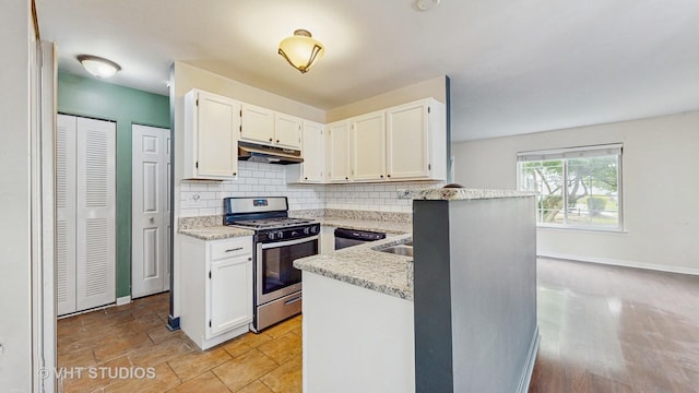 733 Fieldcrest Dr Unit A, South Elgin, IL 60177 - kitchen with stainless steel range with gas stovetop, under cabinet range hood, decorative backsplash, white cabinets, and light stone countertops
