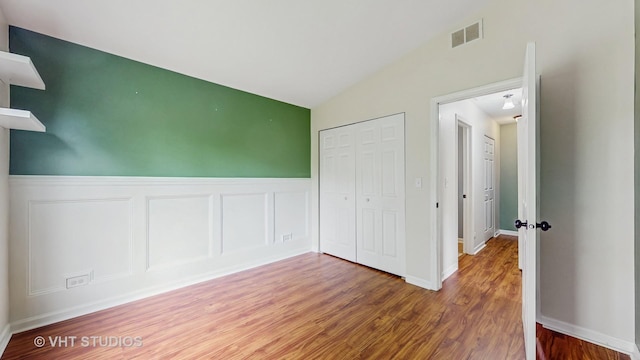 733 Fieldcrest Dr Unit A, South Elgin, IL 60177 - unfurnished bedroom featuring wood finished floors, vaulted ceiling, a closet, and wainscoting