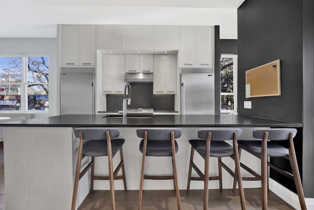 3056 N Monticello Ave, Chicago, IL 60618 - kitchen featuring built in refrigerator, dark countertops, and a kitchen breakfast bar