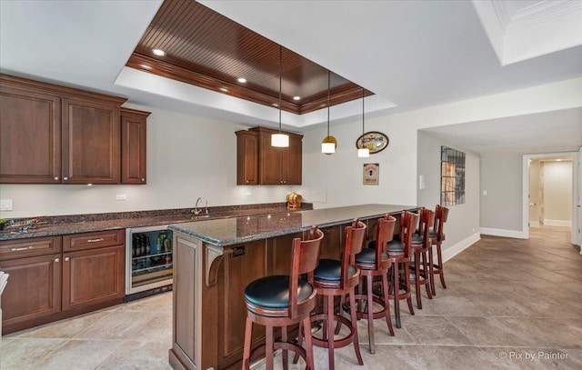 7N627 E Drive S, Elgin, IL 60177 - kitchen featuring wine cooler, a tray ceiling, a breakfast bar area, dark stone countertops, and ornamental molding