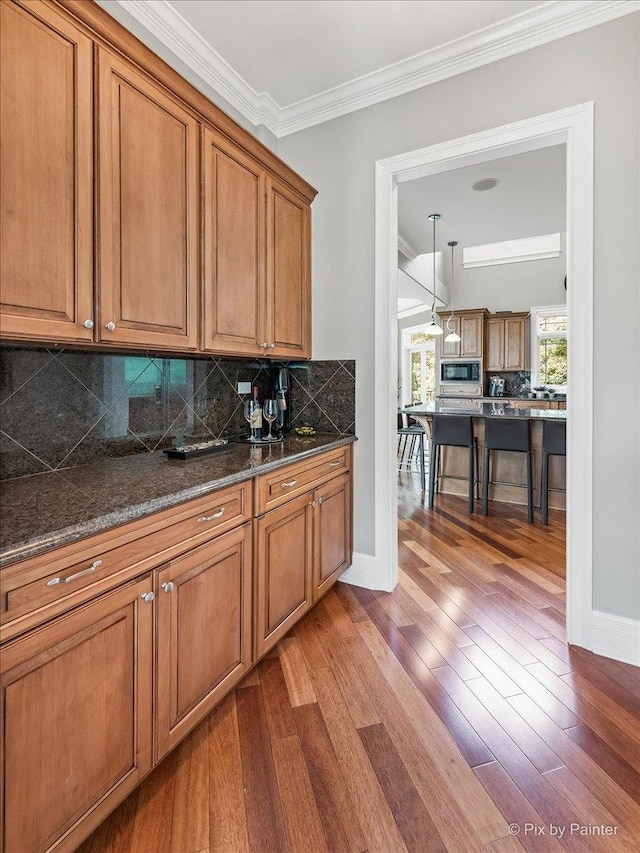 7N627 E Drive S, Elgin, IL 60177 - kitchen featuring built in microwave, brown cabinetry, wood finished floors, decorative backsplash, and ornamental molding