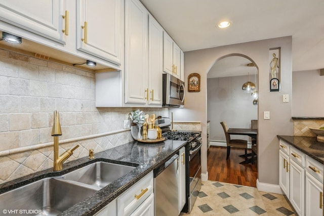 1116 S New Wilke Rd Unit 107, Arlington Heights, IL 60005 - kitchen featuring stainless steel appliances, a sink, arched walkways, dark stone counters, and recessed lighting