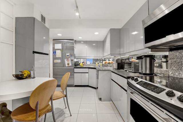1440 N Lake Shore Dr Unit 4Bd, Chicago, IL 60610 - kitchen featuring stainless steel appliances, tasteful backsplash, light tile patterned floors, modern cabinets, and dark countertops
