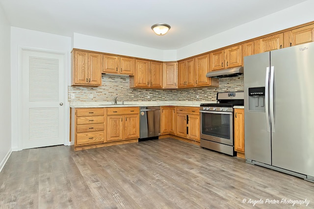 1708 Meadow Ln, Mchenry, IL 60050 - kitchen featuring appliances with stainless steel finishes, a sink, under cabinet range hood, light countertops, and backsplash