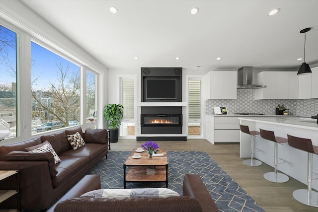 living room with recessed lighting, wood finished floors, and a glass covered fireplace