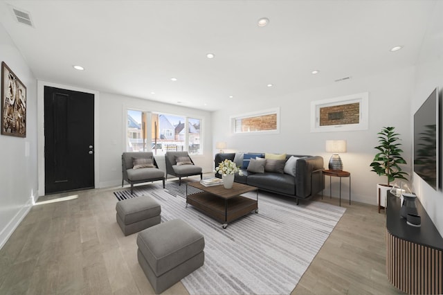 living room with light wood-type flooring, plenty of natural light, recessed lighting, and baseboards