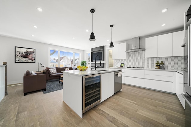 kitchen featuring beverage cooler, wall chimney range hood, modern cabinets, dishwasher, and a sink
